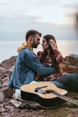 selective focus of man hugging girlfriend near acoustic guitar