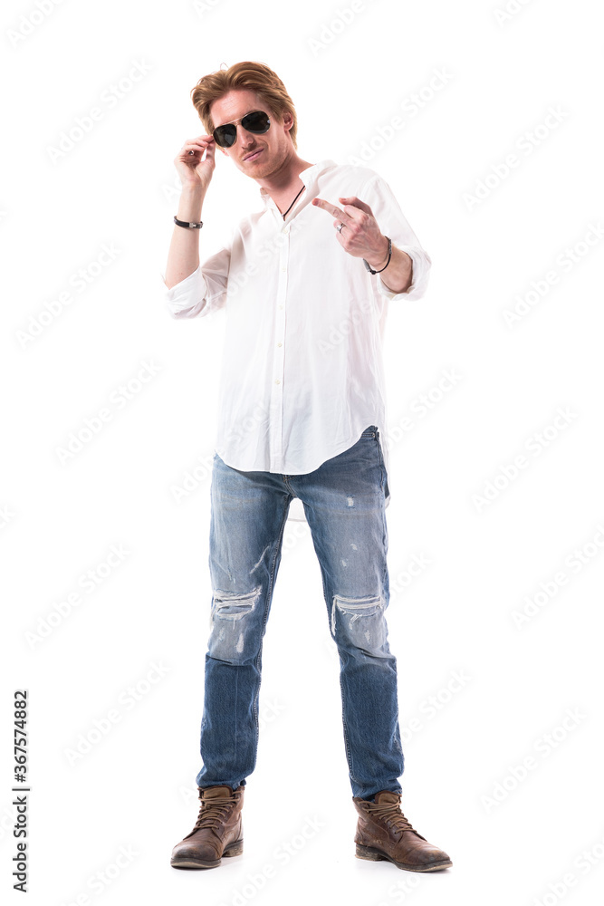 Sarcastic young man smiling and showing rude middle finger gesture at camera. Full body length isolated on white background. Sarcastic young man smiling and showing rude middle finger gesture at camera. Full body length isolated on white background.