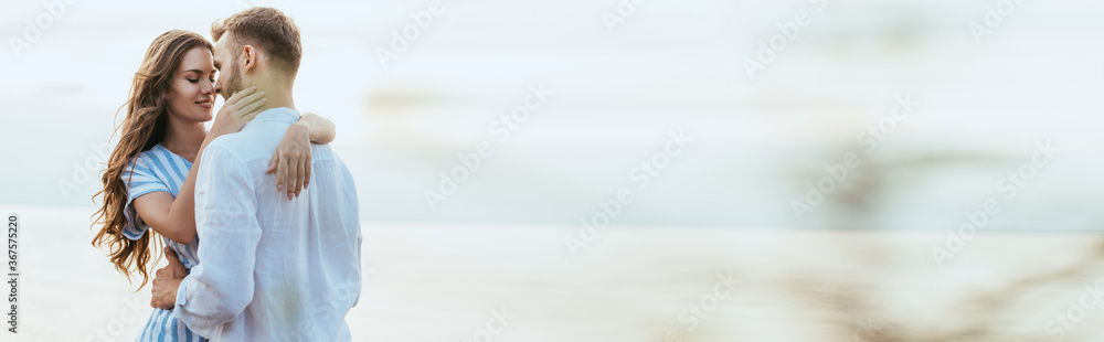 Obraz premium horizontal crop of cheerful woman hugging bearded man near river