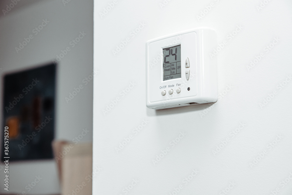 Air conditioner in the room. The concept of cooling the apartment on warm days. White panel for temperature control in a room, office. Air conditioner in the room. The concept of cooling the apartment on warm days. White panel for temperature control in a room, office.
