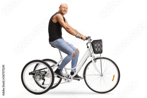 Bald hipster man riding a tricycle and looking at the camera