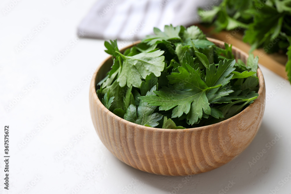 Fresh green parsley in wooden bowl on white table Fresh green parsley in wooden bowl on white table
