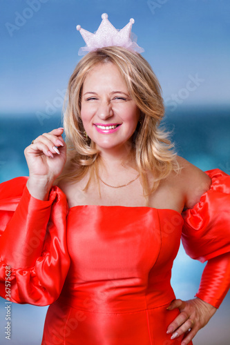 A cheerful blonde woman in a red dress and a princess crown