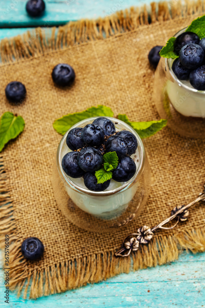 Yogurt with blueberries and chia seeds on wooden cutting board