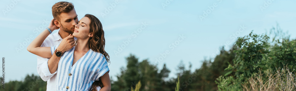 panoramic crop of bearded man kissing happy girl outside panoramic crop of bearded man kissing happy girl outside