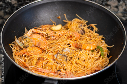 Frying pan with spaghetti and seafood in wok