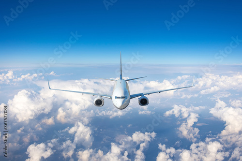 The plane lit by the sun flies straight exactly in the sky above the clouds.