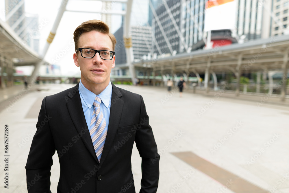 Young handsome blond businessman with eyeglasses in the city outdoors Young handsome blond businessman with eyeglasses in the city outdoors