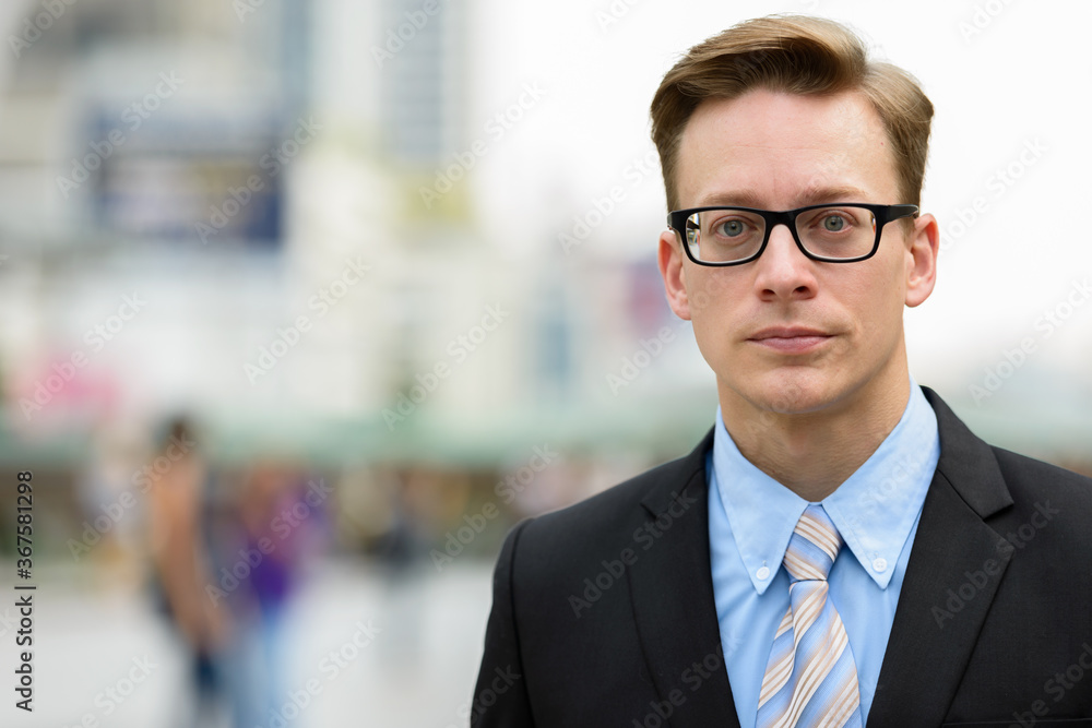 Fototapeta premium Young handsome blond businessman with eyeglasses in the city outdoors