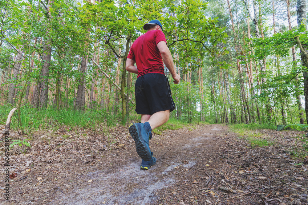 Athlete running on rough terrain in the woods, trail running