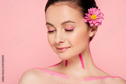 smiling naked beautiful woman with pink lines on body and flower in hair isolated on pink
