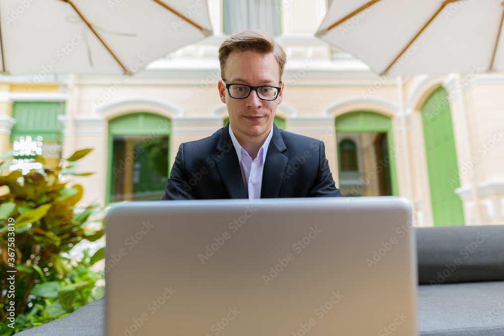 Young handsome blond businessman using laptop at the coffee shop Young handsome blond businessman using laptop at the coffee shop