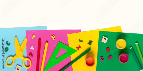 Various school supplies on multicolored bright paper top view. Free space for text, flat lay, banner. Back to school.