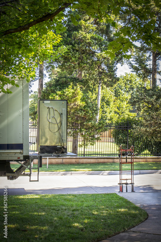 Moving truck with lift gate - older Refrigerator sitting on it and dolly nearby -  in leafy green neighborhood selective focus photo