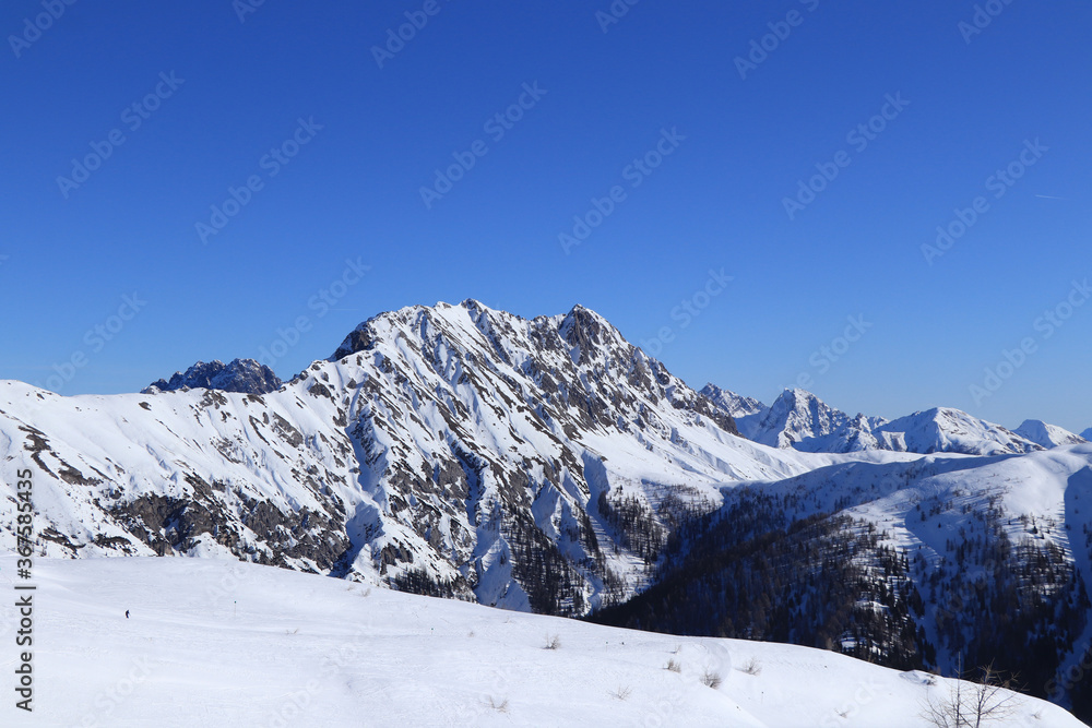 Eggenkofel is dominant of Gaital alps in tyrol, west Austria. Beautiful scenery with snow mountain peaks and blue sky. Skiing in a T-shirt, the need for sunscreen. Rock mountain