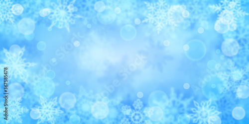 Christmas background of blurry snowflakes in light blue colors