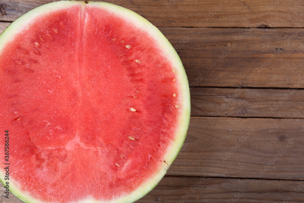 the seedless watermelon - melon cut in half on the wooden table the seedless watermelon - melon cut in half on the wooden table