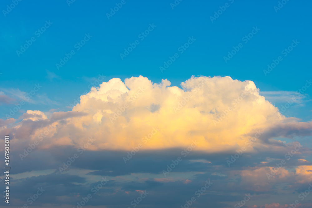 Large white orange cloud against the blue sky at sunset.