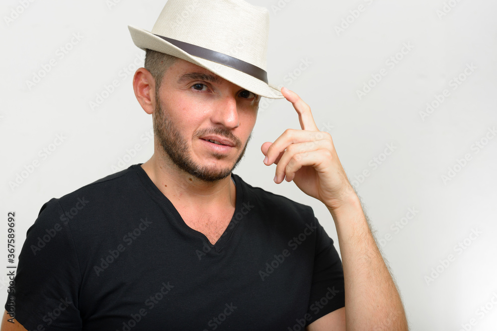 Studio shot of handsome bearded Hispanic man wearing hat Studio shot of handsome bearded Hispanic man wearing hat