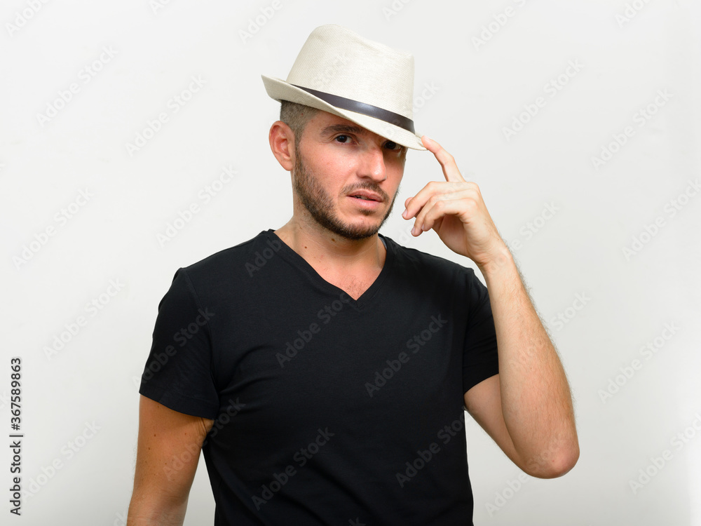 Studio shot of handsome bearded Hispanic man wearing hat Studio shot of handsome bearded Hispanic man wearing hat