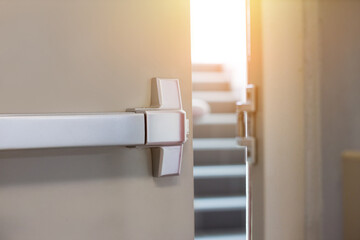 Emergency fire exit door. Closed up latch and rusty door handle of emergency exit. Push bar and rail for panic exit. Open one way door.  steel of handle for the white door fire exit