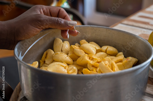 a Jamaican woman's hand  rests on a pan of ackee, one of Jamaica's famous fruits