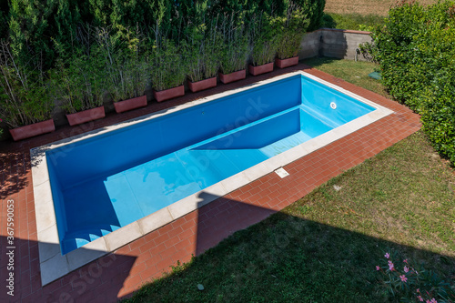 Top view of a swimming pool with blue coating in a private garden completely empty, waiting to be filled with water for the start of the summer season