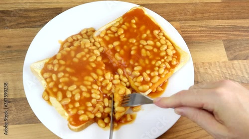 Taking A Bite With A knife And Folk Of Freshly Made Beans On Toast 