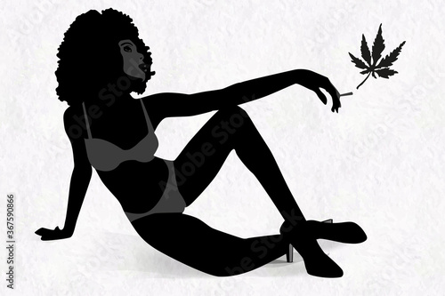 Woman's silhouette with afro hairstyle holding marijhuana leaf in her hand