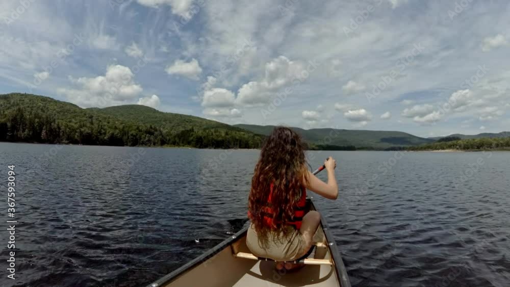 Women paddling at the front of a canoe in lake Women paddling at the front of a canoe in lake