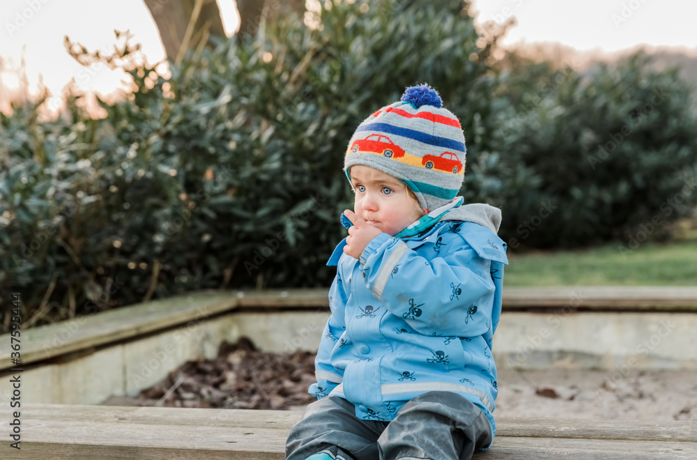 Toddler sitting on wooden bench and pointing Toddler sitting on wooden bench and pointing