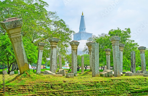 The broken Vatadage pillars with spire of Great Ruwanwelisaya Stupa on background, Anuradhapura, Sri Lanka photo