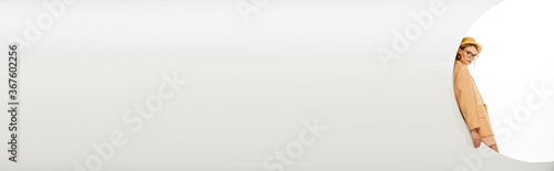 Panoramic shot of stylish woman looking at camera near circle on white background