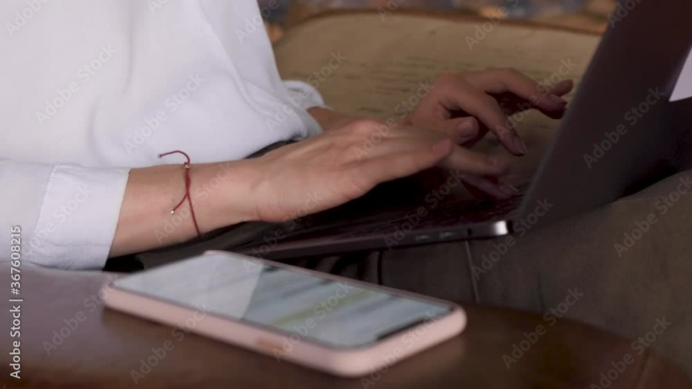 Close Up Of Women's Hands Typing On A Laptop Keyboard Next To A Smartphone Close Up Of Women's Hands Typing On A Laptop Keyboard Next To A Smartphone