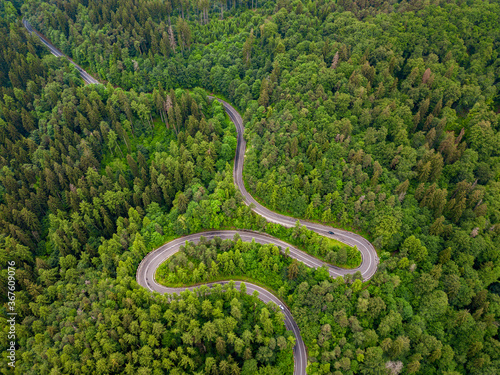 Tarmac road seen from above. Aerial view of an extreme winding road through middle of the forest