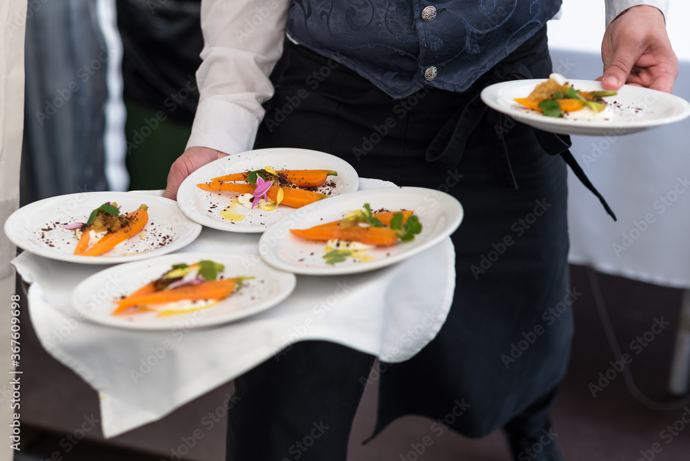 Braised Carrot with Sour Cream, White Fish Roe and Petals. Waiter Serving Food Braised Carrot with Sour Cream, White Fish Roe and Petals. Waiter Serving Food
