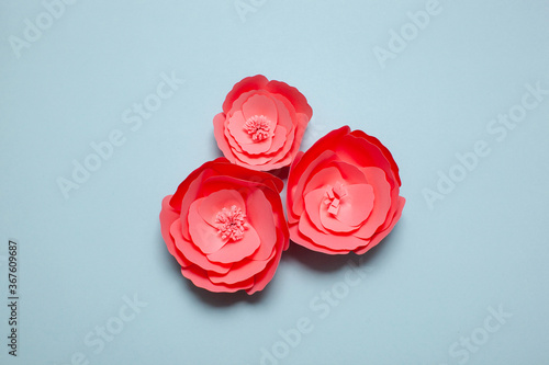 Handmade pink paper art and cutout flowers on blue background. photo