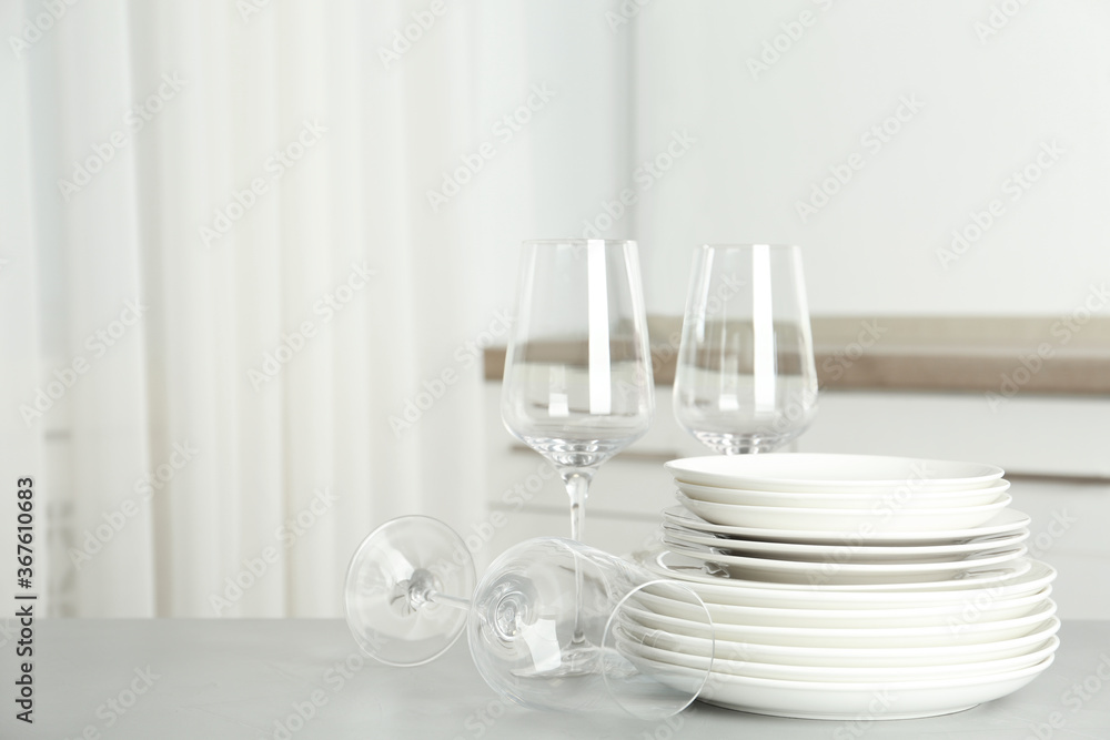 Stack of clean plates and glasses on grey table in kitchen. Space for text Stack of clean plates and glasses on grey table in kitchen. Space for text
