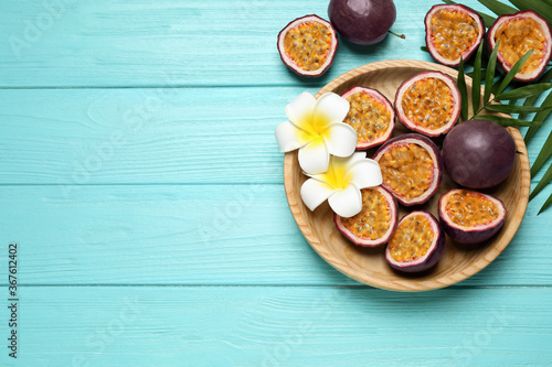Passion fruits (maracuyas), palm leaves and flowers on light blue wooden table, flat lay. Space for text