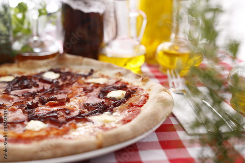 Pizza with ham, red onion jam and goat cheese. Italian cuisine. Traditional Italian pizza. Suggestion to serve a dish. Food background.