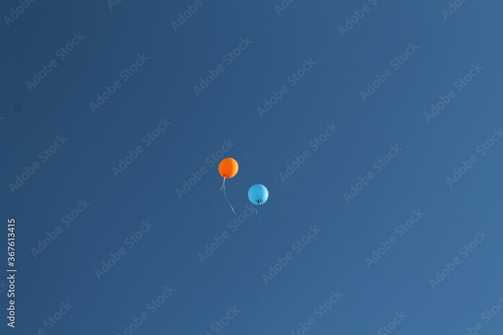 Fototapeta premium two balloons flying through the blue sky