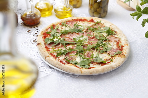 Pizza with ripening ham and arugula. Traditional Italian pizza. Suggestion to serve a dish. Food background.