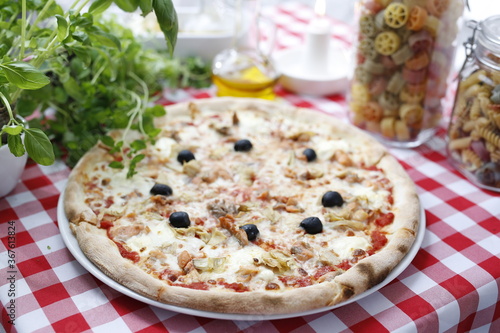 Pizza with tomato sauce, artichokes, black olives, and mozzarella cheese. Italian cuisine. Traditional Italian pizza. Suggestion to serve a dish. Food background.top view,