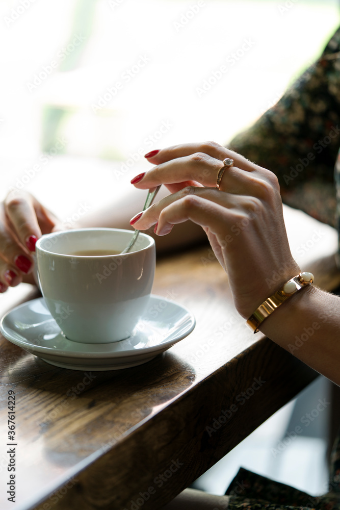 Close-up of a woman's hand holding a cup of hot coffee. Close-up of a woman's hand holding a cup of hot coffee.