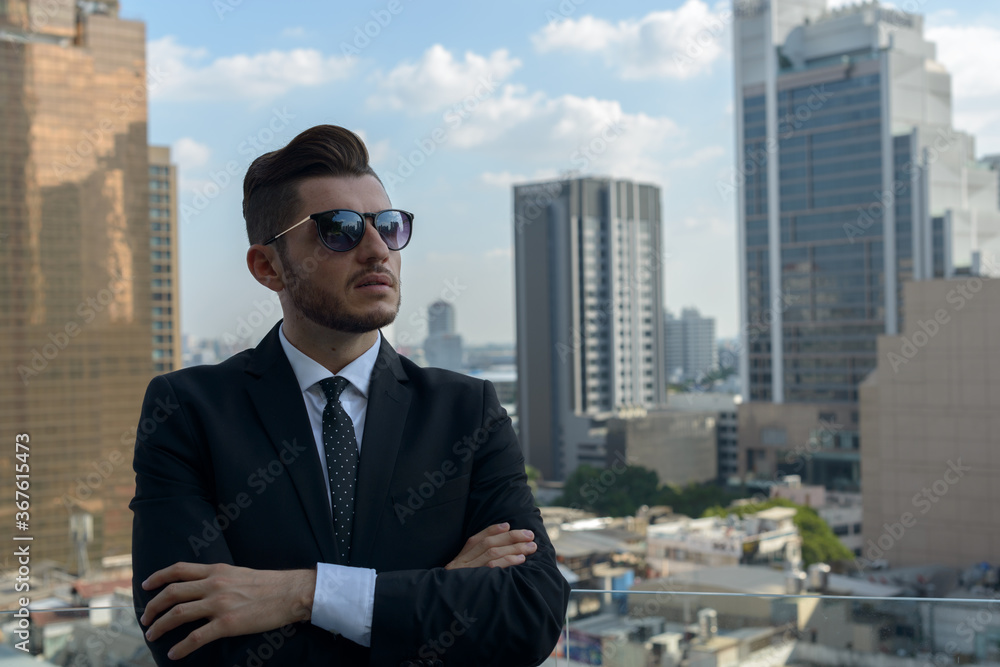 Handsome bearded Hispanic businessman against view of the city Handsome bearded Hispanic businessman against view of the city