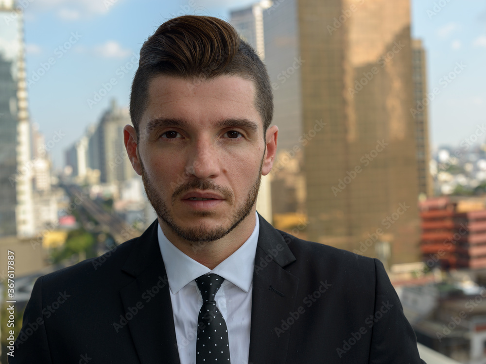Handsome bearded Hispanic businessman against view of the city Handsome bearded Hispanic businessman against view of the city