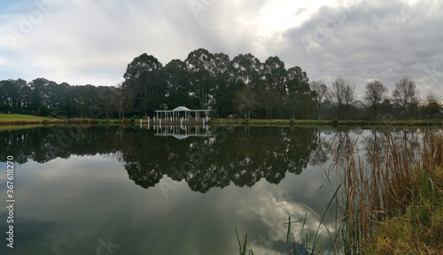 Beautiful morning view of a still pond in a park with stunning reflections of blue puffy sky and tall trees, Fagan park, Galston, Sydney, New South Wales, Australia photo