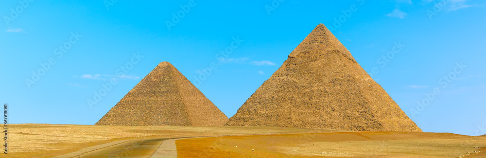 Pyramids at Giza, Egypt protrude majestically into a blue cloudless sky in summer