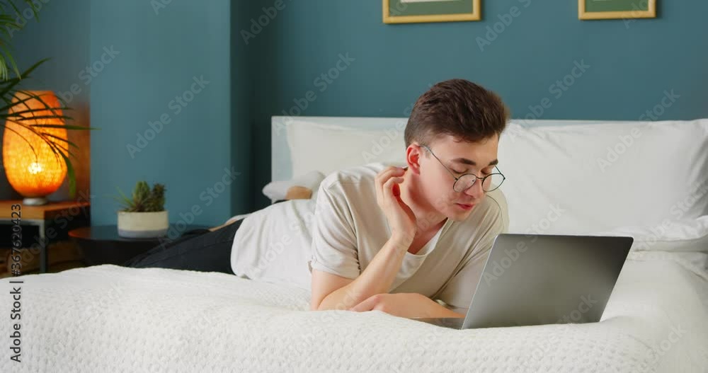 Young man student using laptop looking at computer screen enjoying watching funny social media video, online streaming service, having fun with tech device at home. Young man student using laptop looking at computer screen enjoying watching funny social media video, online streaming service, having fun with tech device at home.
