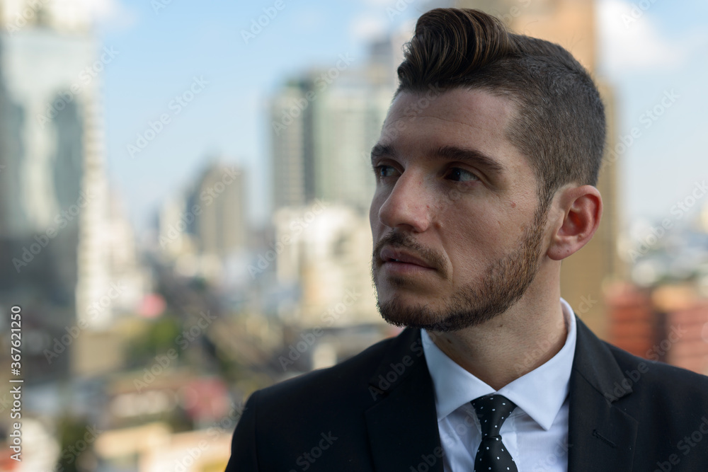 Handsome bearded Hispanic businessman against view of the city Handsome bearded Hispanic businessman against view of the city